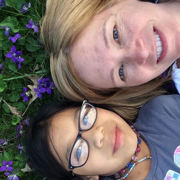 My daughter and I lying in on the front lawn with the violets in bloom